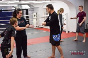 Professor Almeida taking the time to explain grips to a mother and son learning BJJ